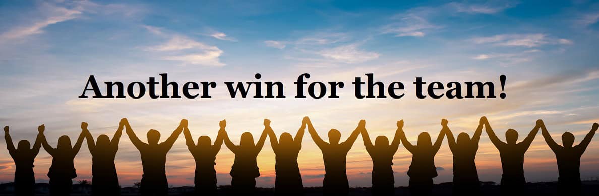 Group of people holding hands at sunset with the text "Another win for the team!".