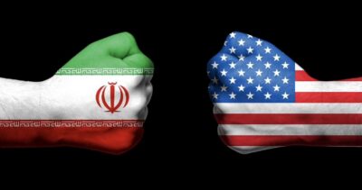 Iran and USA flags painted on fists facing each other.